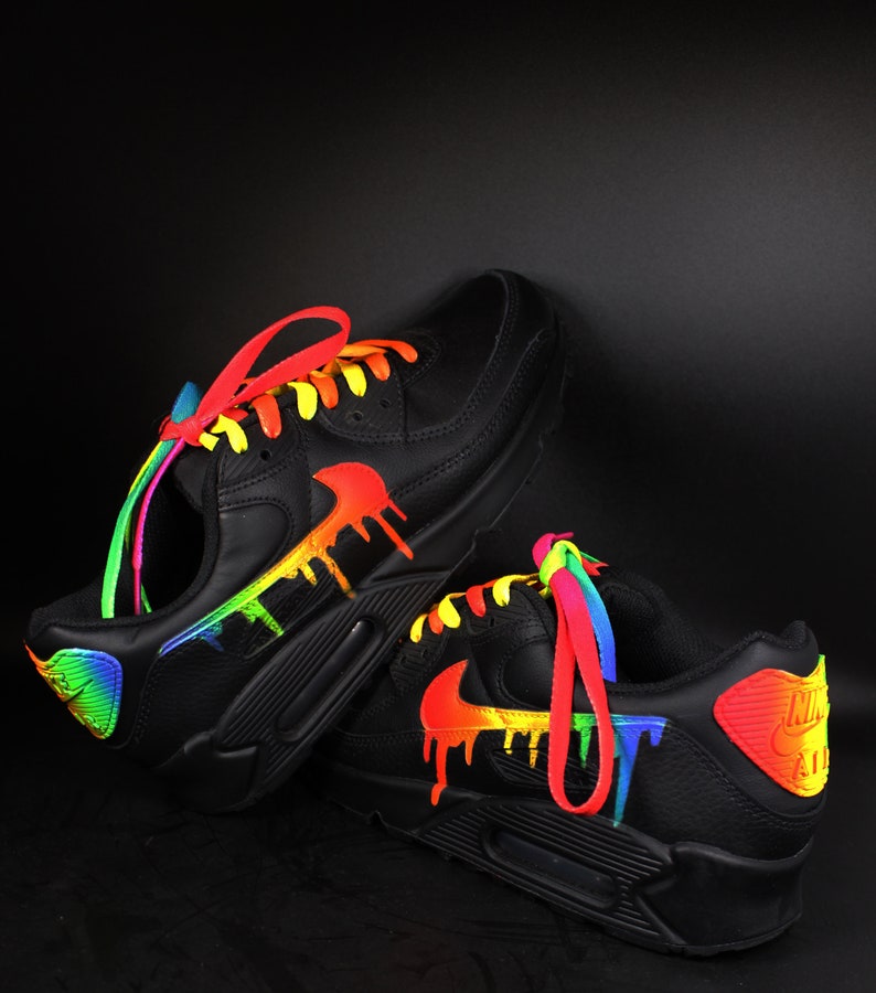 Puede incluir: Zapatillas de cuero negro con detalles de pintura de goteo arco&iacute;ris y cordones de colores.