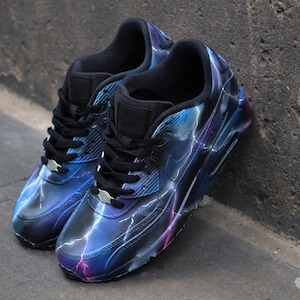 May include: A pair of black sneakers with a blue and purple lightning bolt design. The sneakers have a white swoosh logo on the side.
