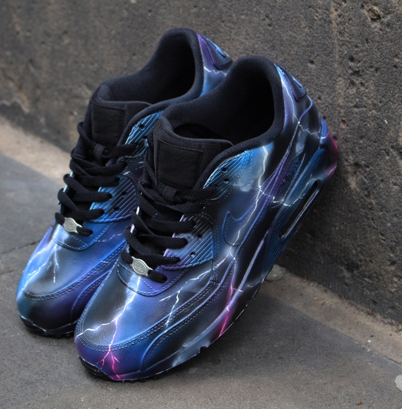 May include: A pair of black sneakers with a blue and purple lightning bolt design. The sneakers have a white swoosh logo on the side.
