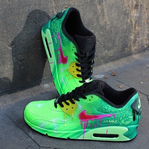 Puede incluir: Un par de zapatillas Nike Air Max 90 verdes, negras y rosas con un dise&ntilde;o de pintura personalizado. Las zapatillas presentan un patr&oacute;n de rayo, pintura goteando y un dise&ntilde;o floral.