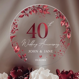 Puede incluir: Un topper de pastel de acrílico transparente con un diseño floral rojo y el texto "40º Aniversario de Boda John & Jane 09.18.1984".