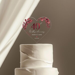 May include: A clear heart-shaped cake topper with a red 40th anniversary design. The topper features a red floral design and the text "40th Wedding Anniversary John & Jane 09.18.1984".
