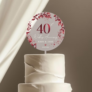 May include: A round cake topper with a burgundy floral design and the text "40th Wedding Anniversary John & Jane 09.18.1984".