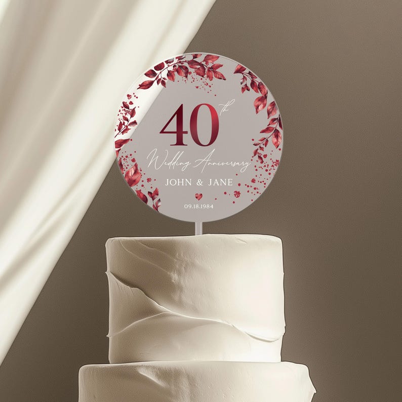 May include: A round cake topper with a burgundy floral design and the text "40th Wedding Anniversary John & Jane 09.18.1984".
