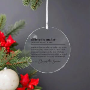 May include: A clear round bauble with the definition of "difference maker" and the name "Elizabeth Brown" printed on it.