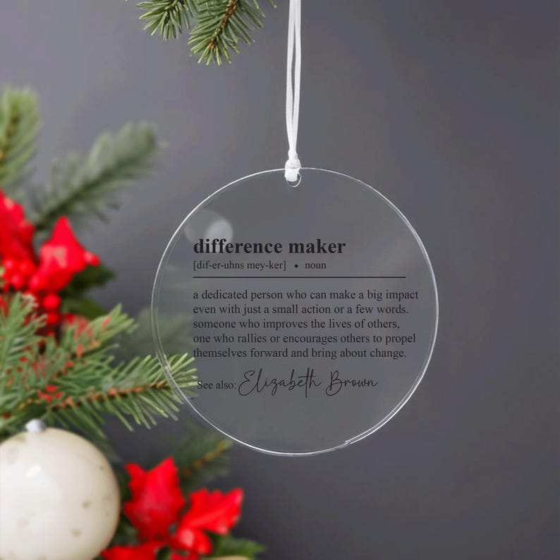 May include: A clear round bauble with the definition of "difference maker" and the name "Elizabeth Brown" printed on it.