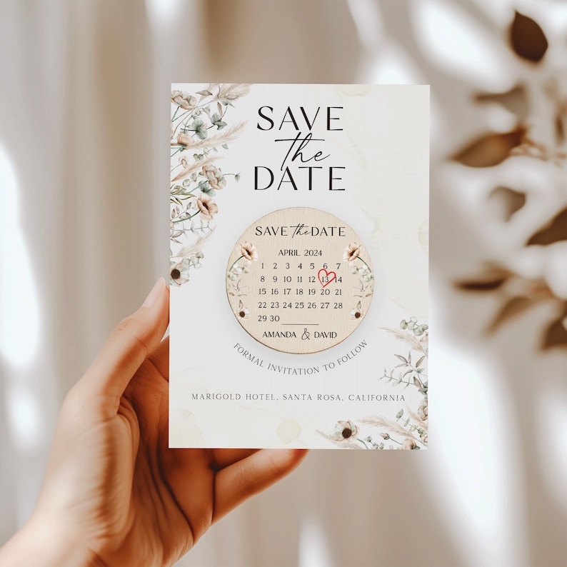 Puede incluir: Tarjeta de guardar la fecha con un dise&ntilde;o floral y un c&iacute;rculo de madera con un calendario que muestra abril de 2024 con un coraz&oacute;n marcando el 13. El texto dice "Save the Date" y "Amanda & David" con la ubicaci&oacute;n "Marigold Hotel, Santa Rosa, California".