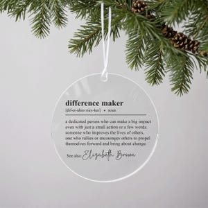 May include: A clear round bauble with the definition of "difference maker" and the name "Elizabeth Brown" printed on it.