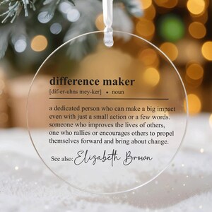 May include: A clear round bauble with the definition of "difference maker" and the name "Elizabeth Brown" printed on it.