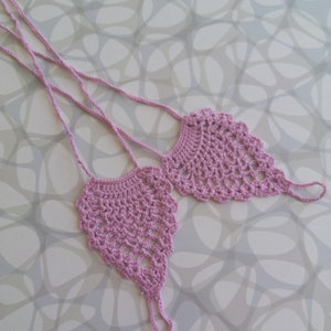 May include: A pair of crocheted foot jewelry in a light purple color. The jewelry is made of delicate crocheted lace and has a dangling design.
