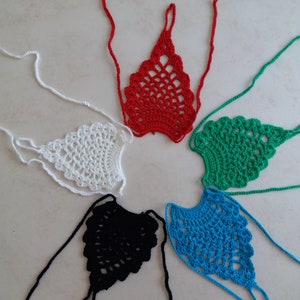 May include: Five crocheted foot covers in different colors: red, white, green, black, and blue. Each foot cover has a delicate, lacy design and is tied with long strings.
