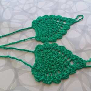 May include: A pair of green crocheted foot jewelry with a delicate design. The jewelry is made of a soft, lightweight yarn and is perfect for adding a touch of bohemian style to any outfit.