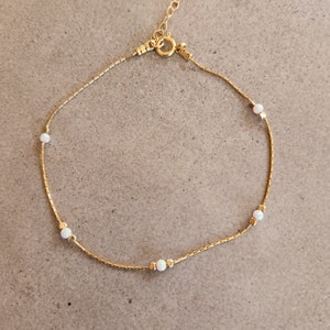 May include: A delicate gold chain anklet with five small white opal stones.