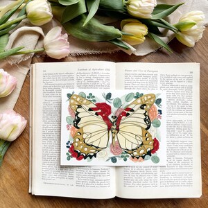 May include: A vintage book open to a page with a colourful illustration of a butterfly surrounded by flowers. The text on the page discusses the use of fumigants in agriculture.