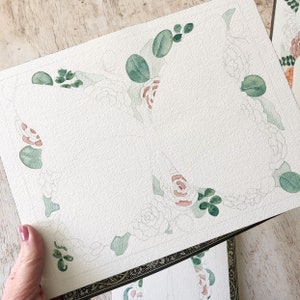May include: A watercolour painting of a floral border with green leaves and pink flowers. The painting is on a white background and is unfinished.