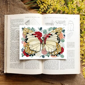 May include: A watercolour illustration of a butterfly with red, white, and gold wings. The butterfly is surrounded by pink, red, and white flowers. The image is from a book titled "Yearbook of Agriculture 1932".