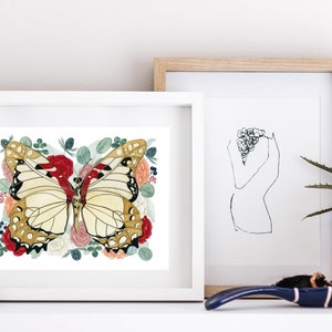 May include: A white framed print featuring a watercolour painting of a butterfly with red, white, and gold wings surrounded by red, white, and pink flowers and green leaves.