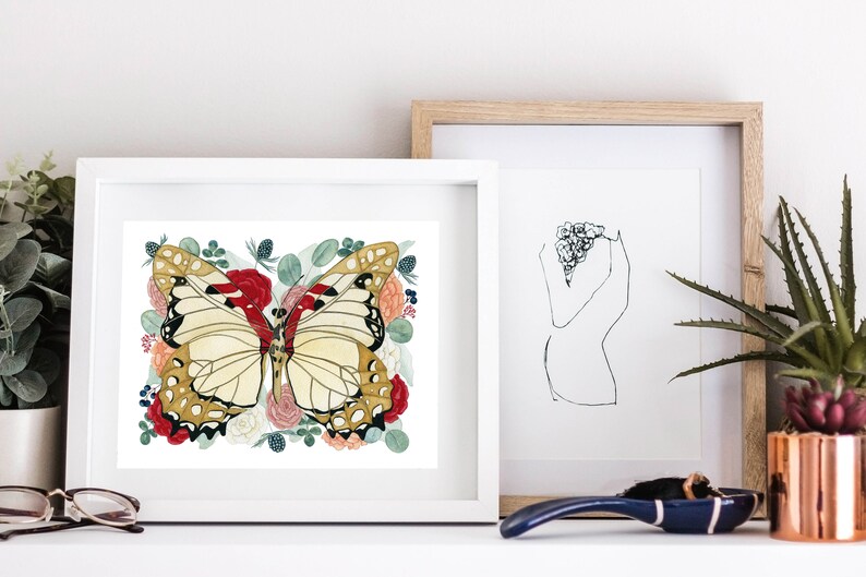 May include: A white framed print featuring a watercolour painting of a butterfly with red, white, and gold wings surrounded by red, white, and pink flowers and green leaves.