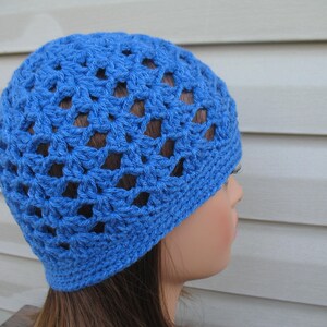 Peut inclure: Un bonnet en crochet bleu avec un motif ajour&eacute;. Le bonnet est fait d'un fil doux et a une coupe confortable.