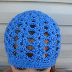 Peut inclure: Un bonnet en crochet bleu avec un motif ajour&eacute;.