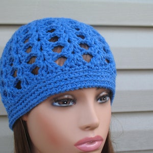 Peut inclure: Un bonnet bleu en crochet avec un motif ajour&eacute;. Le bonnet est sur une t&ecirc;te de mannequin.