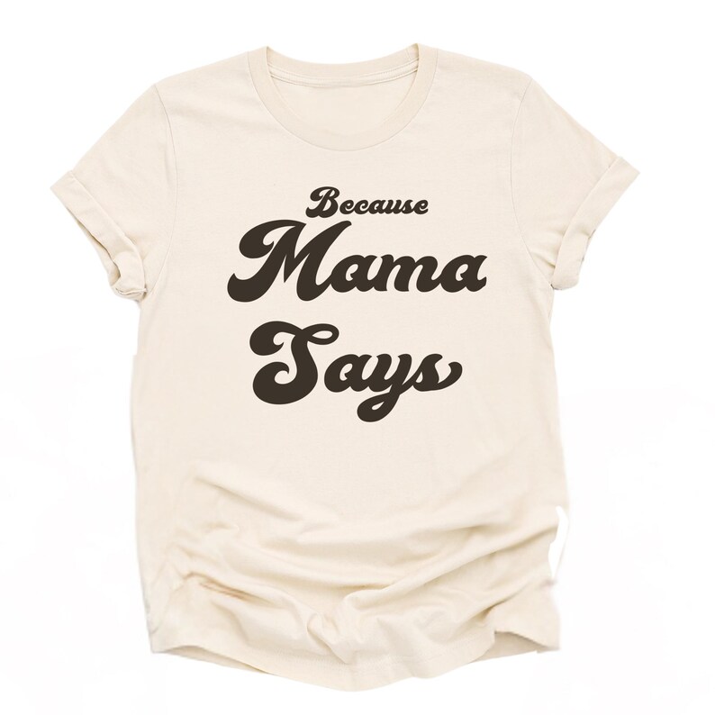 May include: A beige t-shirt with the text "Because Mama Says" in a retro font.