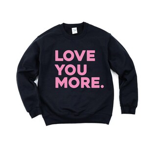 May include: Black sweatshirt with the words "LOVE YOU MORE" printed in pink.