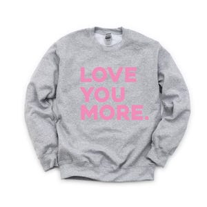 May include: A gray sweatshirt with the words "LOVE YOU MORE" printed in pink.
