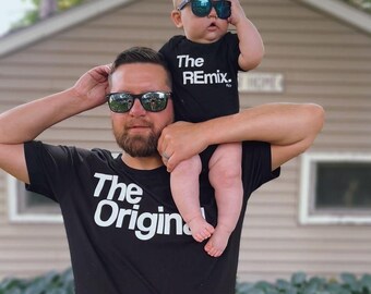 May include: A father and son wearing matching black t-shirts. The father's shirt says "The Original" and the son's shirt says "The Remix." Both are wearing sunglasses.