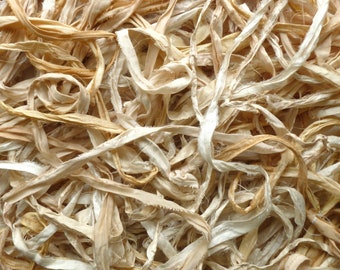 May include: A pile of off-white and beige fabric scraps, some of which are twisted into loops. The fabric is thin and appears to be made of cotton.