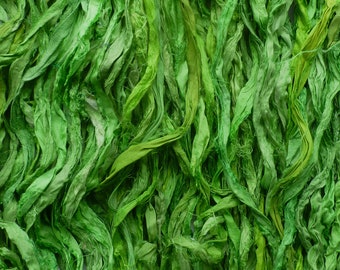 May include: A close-up of a bundle of green silk ribbon, with a soft, textured appearance. The ribbon is arranged in a random, flowing pattern, creating a visually appealing and organic texture.