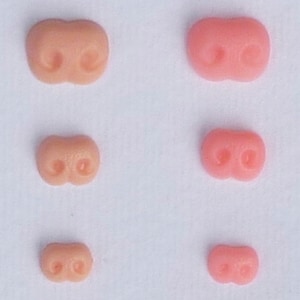 May include: Five different sizes of pink and flesh-toned plastic noses for crafts or doll making.