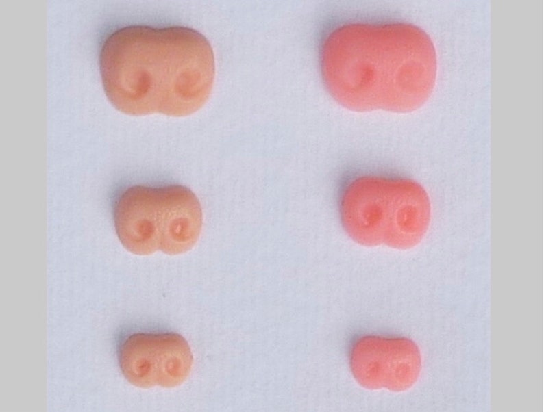 May include: Five different sizes of pink and flesh-toned plastic noses for crafts or doll making.