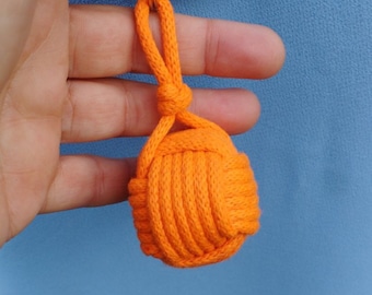 Op de afbeelding: Oranje sleutelhanger gemaakt van geknoopt touw met een zilveren sleutelring.