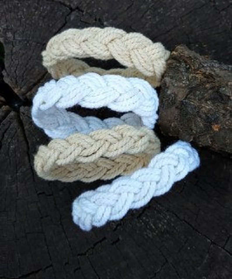 May include: Four braided rope bracelets in white and beige colors. The bracelets are stacked on top of each other.