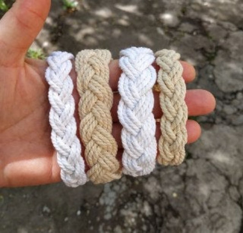 May include: Four braided rope bracelets in two colors: white and beige. The bracelets are made of thick, woven rope and are a simple, stylish accessory.
