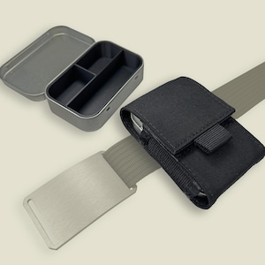 May include: A metal tin with a divided interior and a separate lid, next to a black pouch attached to a gray belt. The pouch has a flap closure. A silver metal belt buckle is also visible.