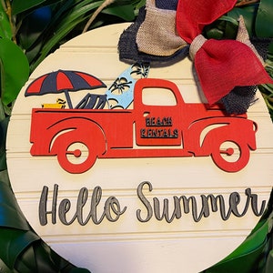 Pu&ograve; includere: Un cartello rotondo di legno con un camioncino rosso che trasporta tavole da surf e un ombrello. Il camioncino ha la scritta "Beach Rentals" sul lato. Il cartello ha anche la scritta "Hello Summer" in lettere nere.