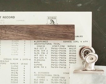 May include: A close-up of a student record card with a silver binder clip. The card lists courses, dates, and grades for an architectural technology programme. The text on the card includes "M. Difranco Architectural Tech. Course Bld Est 2 79/01-79/04 AR237".