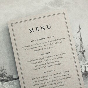 May include: A rustic menu card with a black border and the word 'MENU' in large black letters. The menu lists artisan bakery selections, an appetizer, and a main course. The menu is printed on a textured, beige paper with a drawing of a ship in the background.