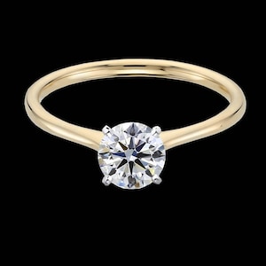 Puede incluir: Un anillo de compromiso de banda simple de oro con un diamante redondo brillante.
