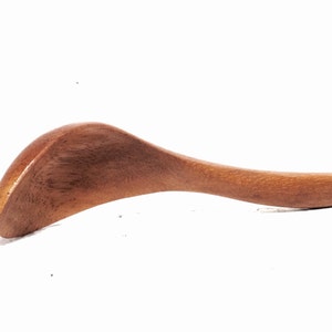 May include: A wooden gua sha tool with a curved shape and a smooth, polished surface.