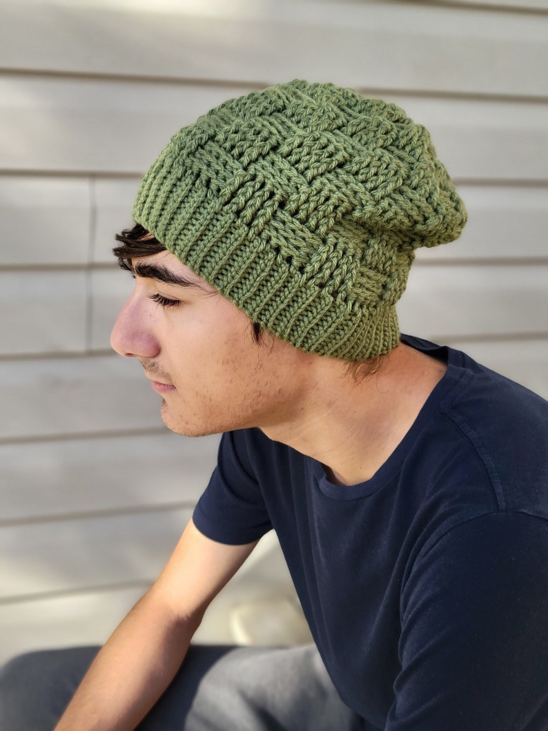 May include: A green crocheted beanie with a textured pattern. The beanie is worn by a person with dark hair.