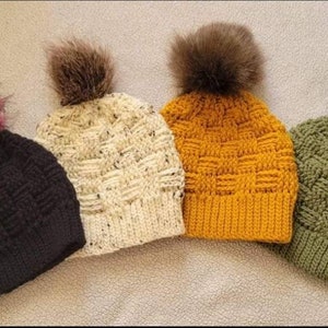 May include: Four crocheted hats with faux fur pom poms in black, white, yellow, and green.