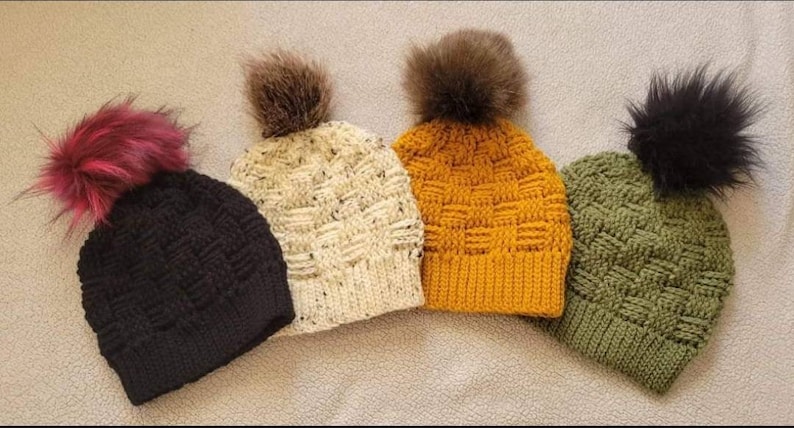 May include: Four crocheted hats with faux fur pom poms in black, white, yellow, and green.