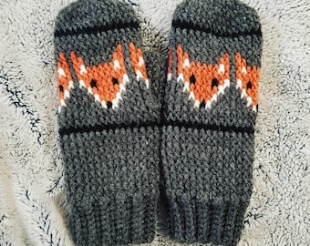 Puede incluir: Un par de guantes de punto grises con un diseño de zorro en naranja, blanco y negro.