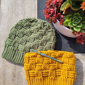 May include: Two crocheted hats, one green and one yellow, with a crochet hook laying across the yellow hat.