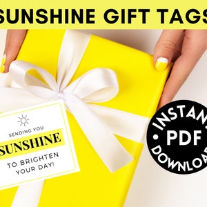 Puede incluir: Una caja de regalo amarilla con una cinta blanca y una etiqueta de regalo blanca que dice "Sending you sunshine to brighten your day!"  La etiqueta de regalo está atada a la cinta con un pequeño icono de sol.  La caja de regalo está sobre una superficie blanca.  El texto "INSTANT PDF DOWNLOAD" está en un círculo negro.