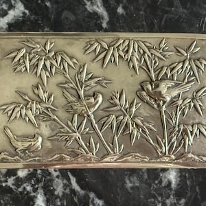 May include: Rectangular silver-toned box with a detailed relief of birds and bamboo. The design features three birds perched among bamboo stalks and leaves, creating a nature-inspired scene. The box has a simple, clean border.