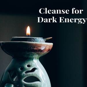 Puede incluir: Una vela encendida en un quemador de aceite de cerámica decorativo. El quemador es verde y marrón con un diseño único. El texto "Cleanse for Dark Energy" se muestra encima de la vela.